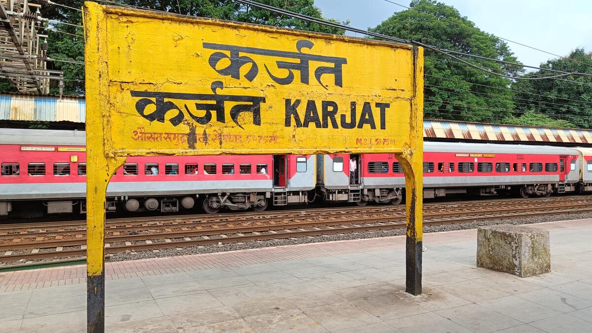 Karjat Railway Station signboard with passenger train on platform in Maharashtra