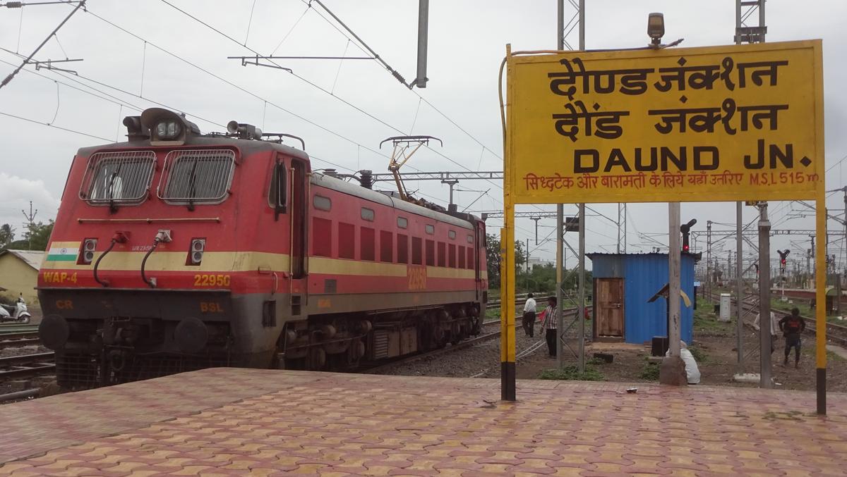 WAP-4 electric locomotive near Daund Junction signboard with railway tracks and overhead lines