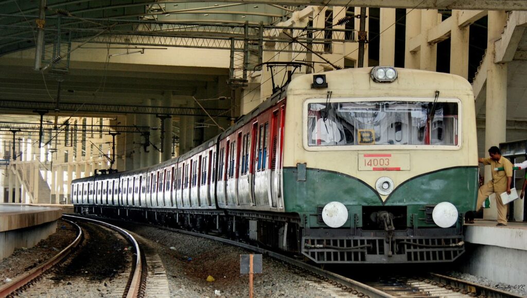 Indian suburban EMU train arriving at platform with curved track and station infrastructure