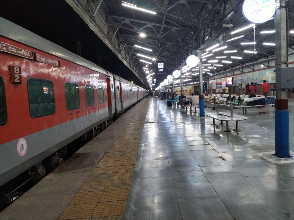Indian railway platform at night with LHB coach train and passengers waiting