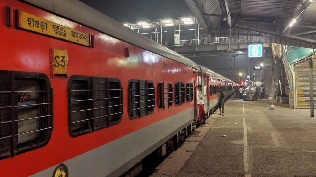 Indian Railways express train at night platform with passengers boarding under station lights