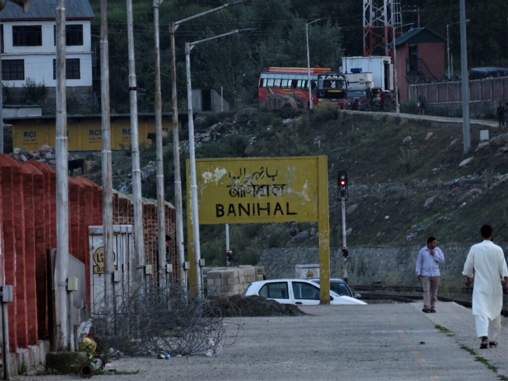 Banihal railway station signboard with tracks, people, and hilly surroundings in Jammu and Kashmir