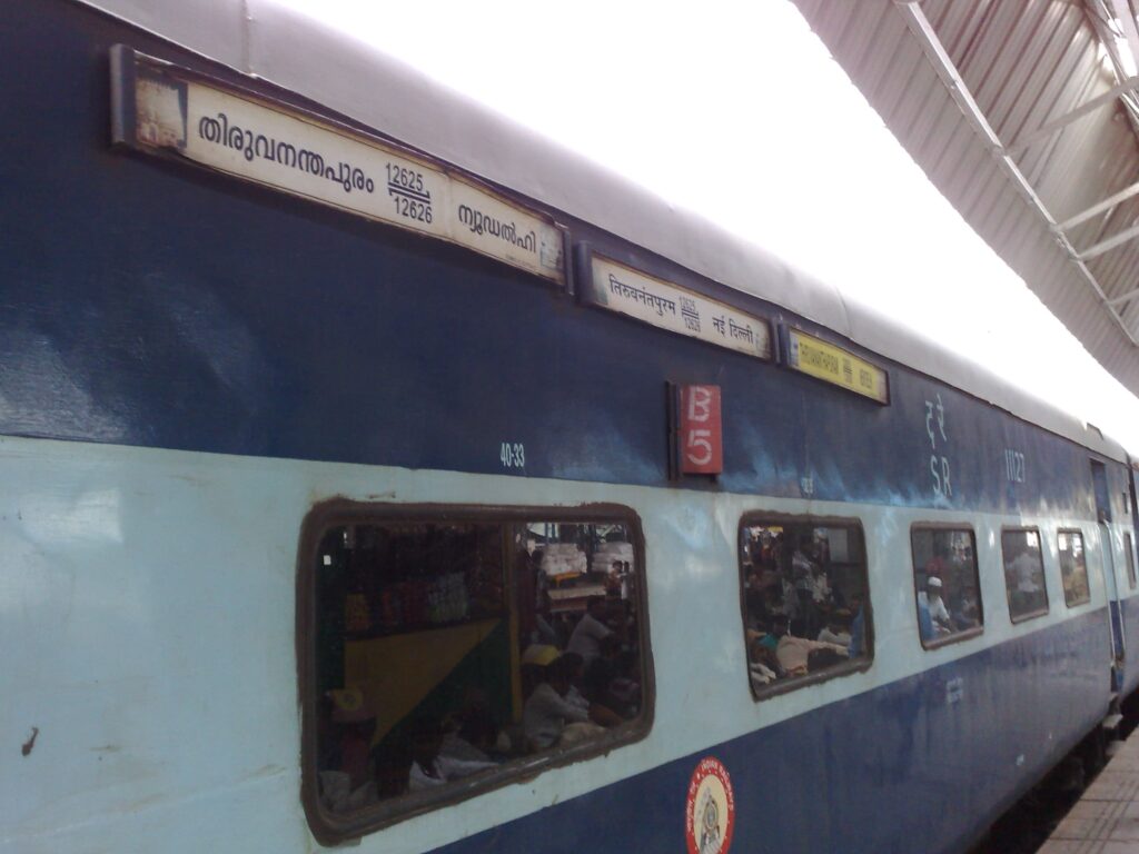 Indian Railways blue sleeper class coach at station platform with passengers
