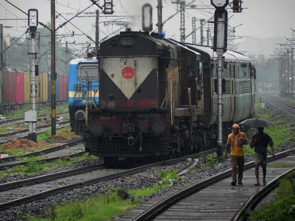 Indian Railways diesel locomotive on busy multi-track route with freight and passenger trains in background