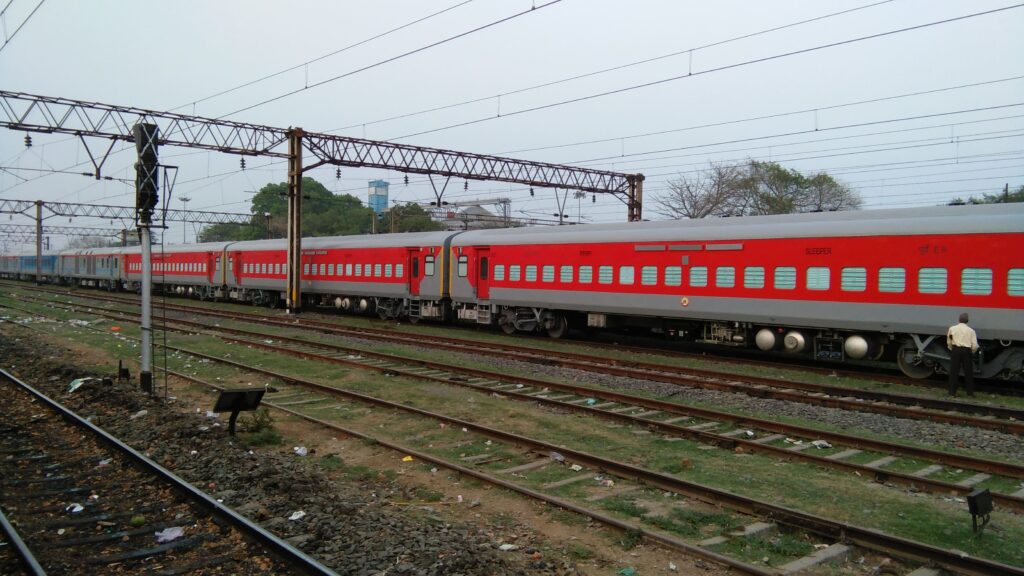 Indian Railways red LHB passenger coaches train on electrified railway tracks