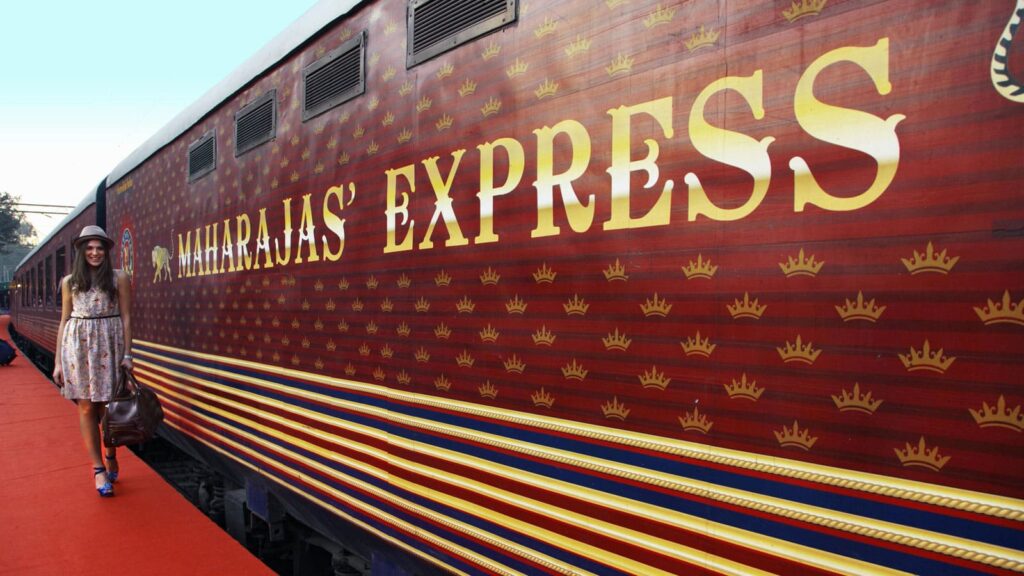 Maharajas’ Express luxury train exterior with royal red design and passenger boarding at platform