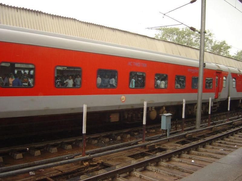 LHB coach train in India with passengers visible through windows at railway track
