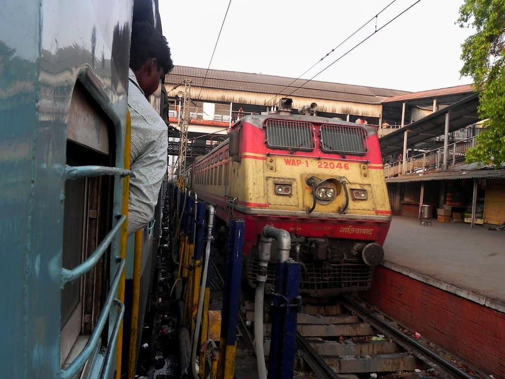 Indian Railways electric locomotive at station platform with passenger looking out of train window