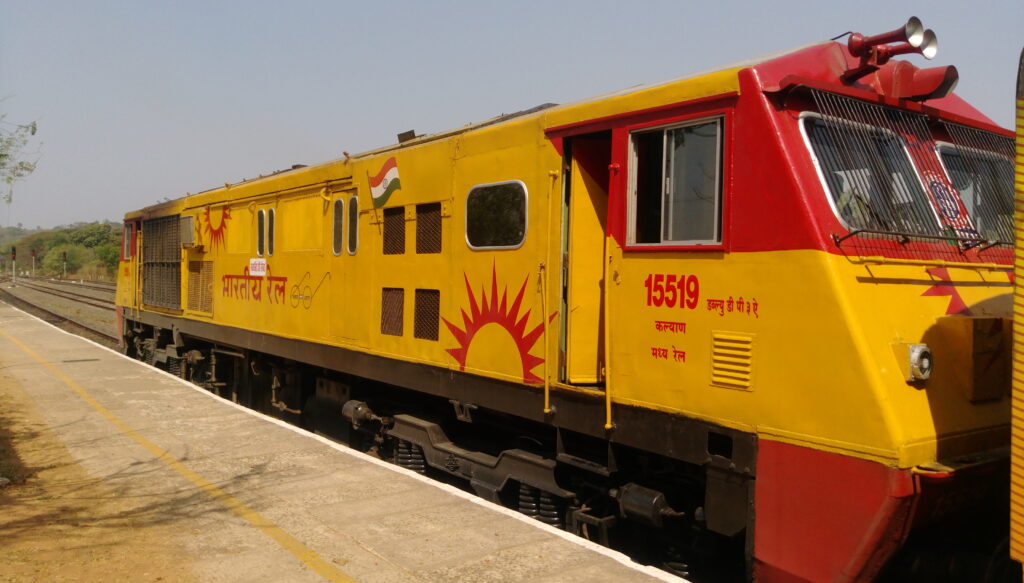 Indian Railways yellow electric locomotive standing at railway station platform