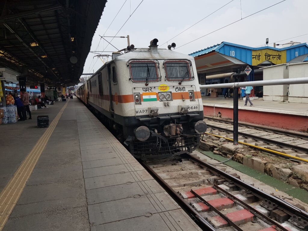 Indian Railways WAP7 electric locomotive at New Delhi railway station platform with passenger train