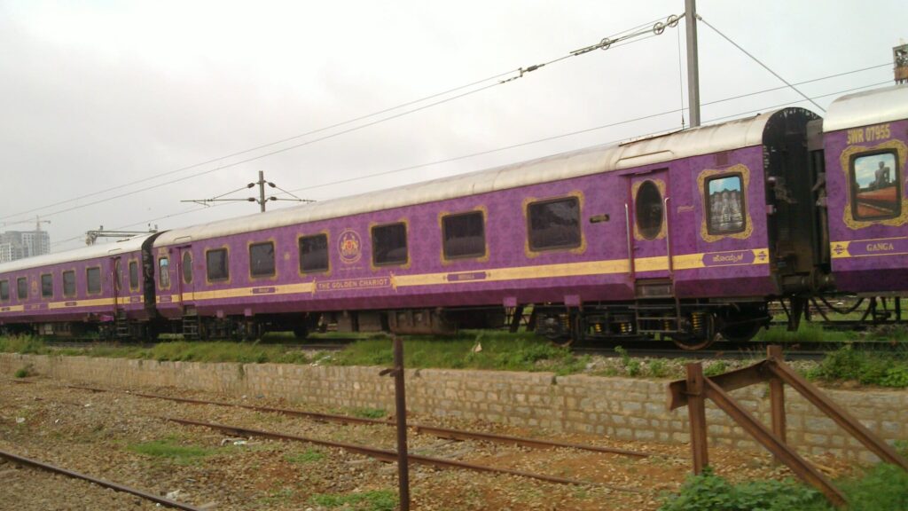 Golden Chariot luxury train with purple coaches running on Indian railway tracks