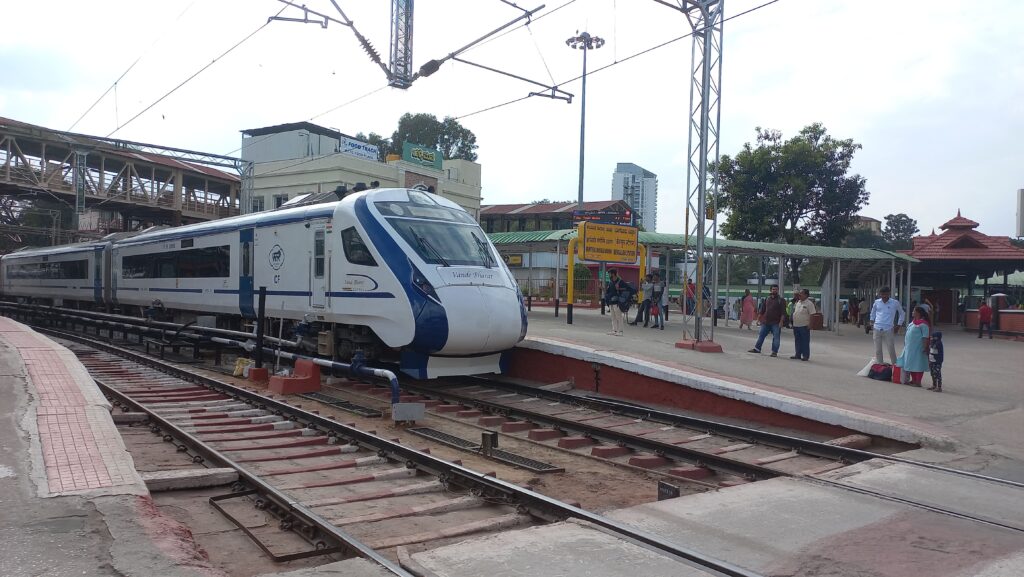 Vande Bharat Express train standing at Indian railway station platform with passengers nearby